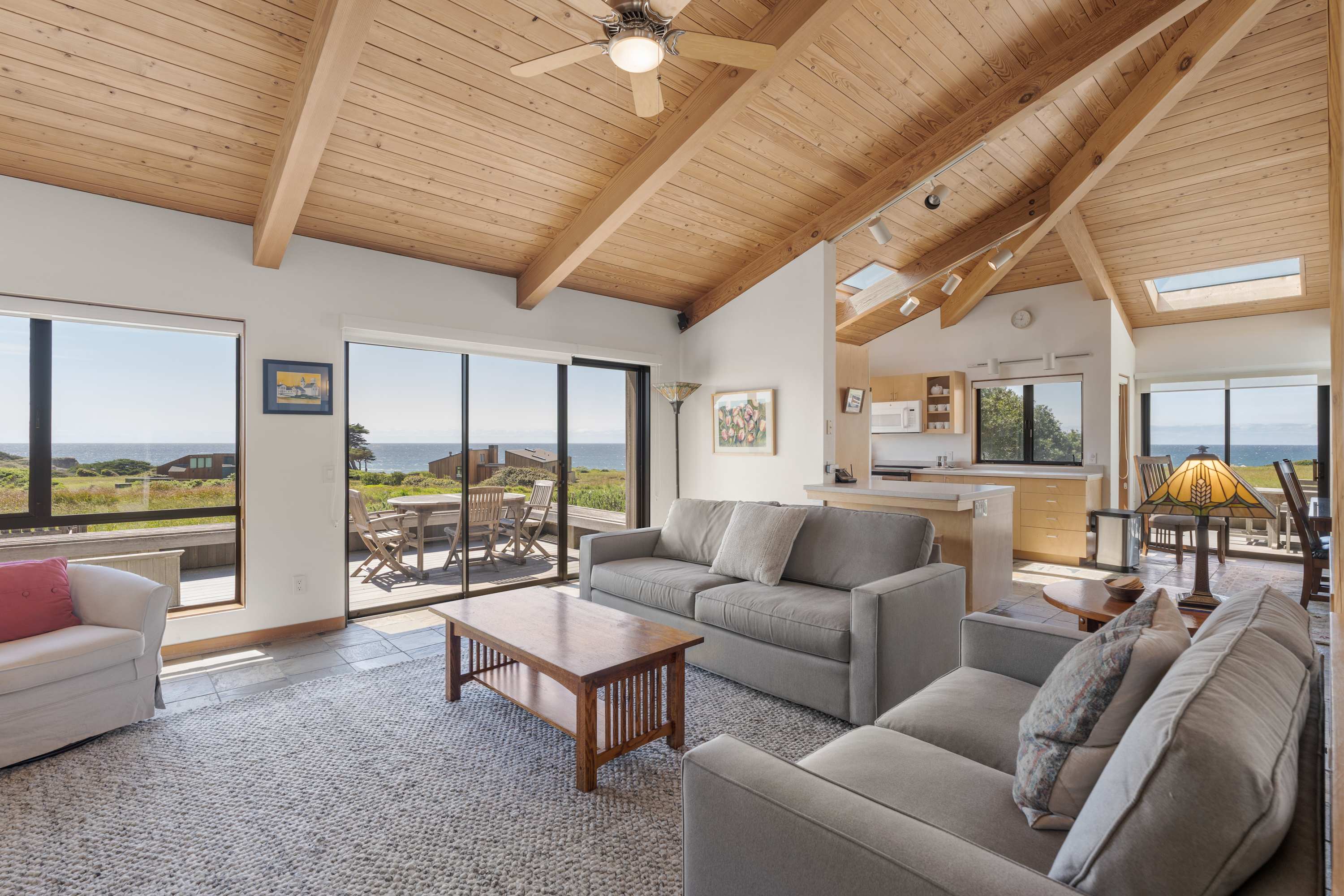 Sink into the sofa and take in sweeping ocean views through floor-to-ceiling glass, where the vaulted wood ceiling and natural light set the tone for your Sea Ranch escape.
