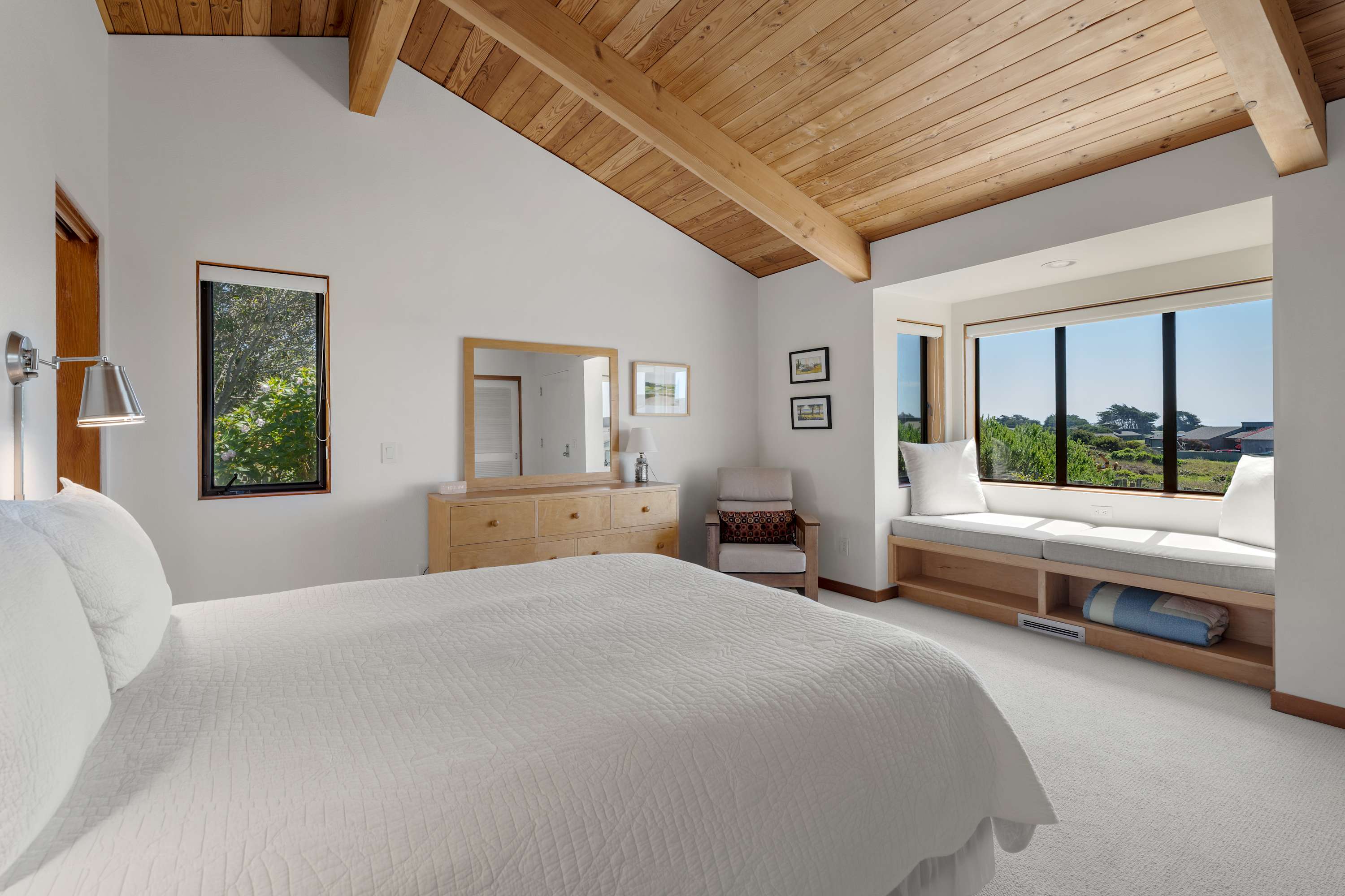 Retreat to the primary bedroom, where vaulted wood ceilings and a built-in window seat with coastal views invite you to slow down and relax.