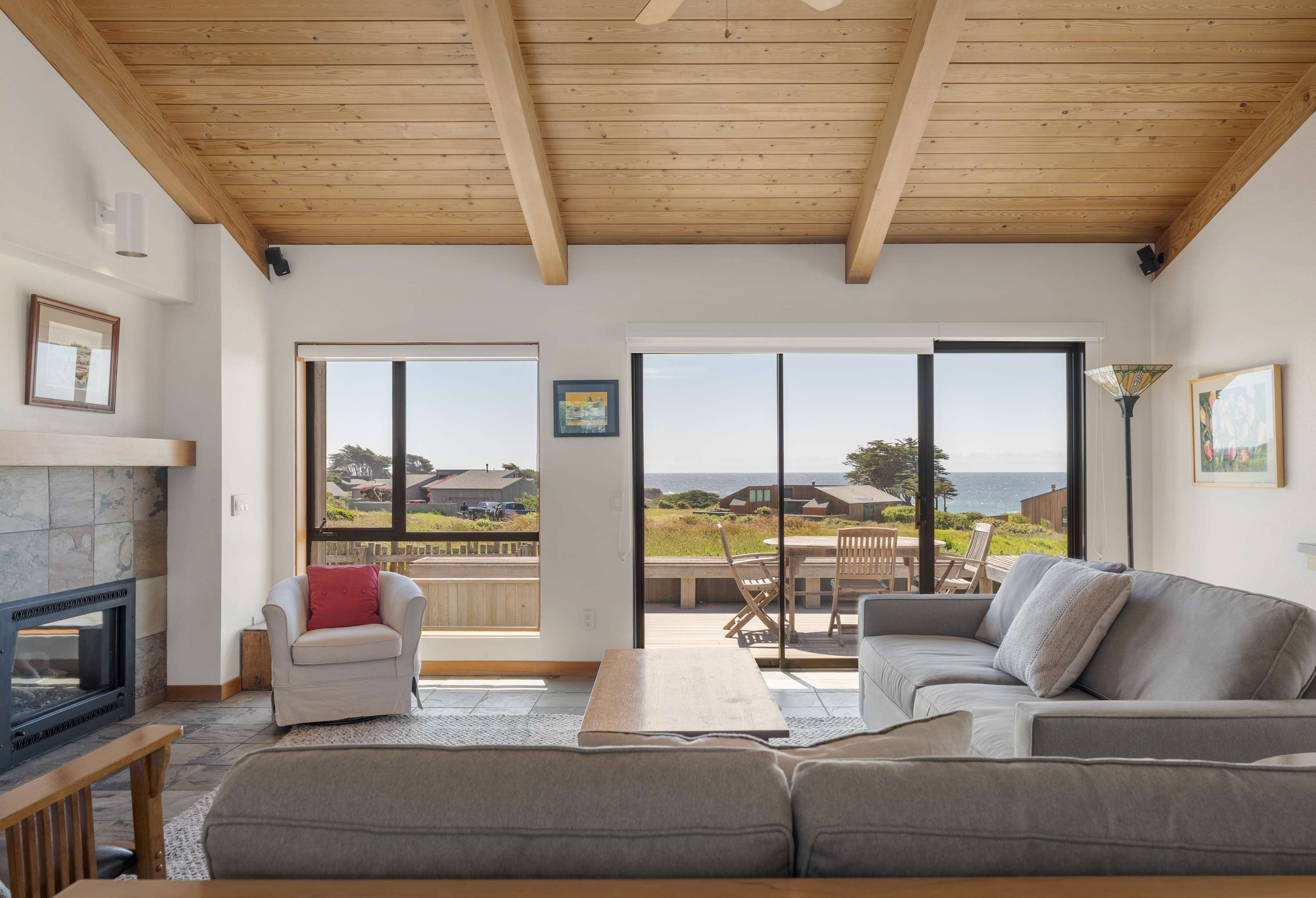 Cozy up by the stone fireplace on cool coastal evenings, with ocean views and the deck just steps away through the sliding glass doors.