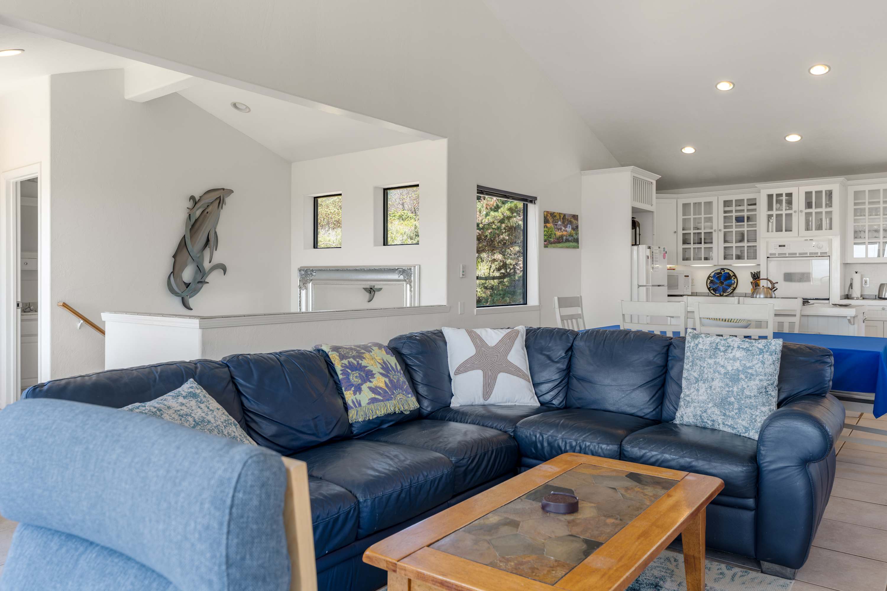 Stretch out on the wraparound sectional beneath soaring ceilings, where playful coastal touches and an open kitchen keep everyone connected.