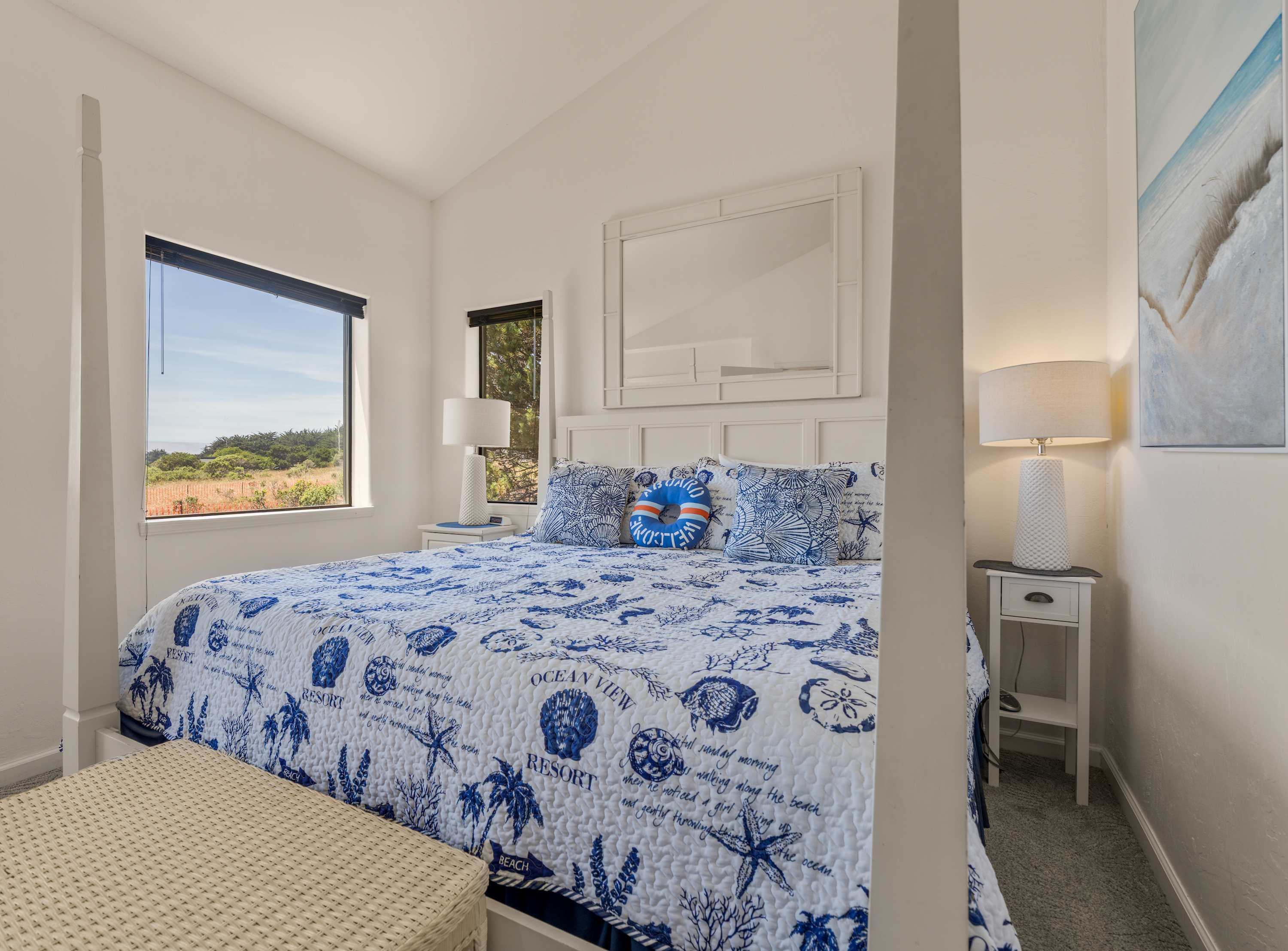 Wake to meadow light in this serene bedroom, where a coral-print quilt and soft lamplight invite slow, salt-air mornings.