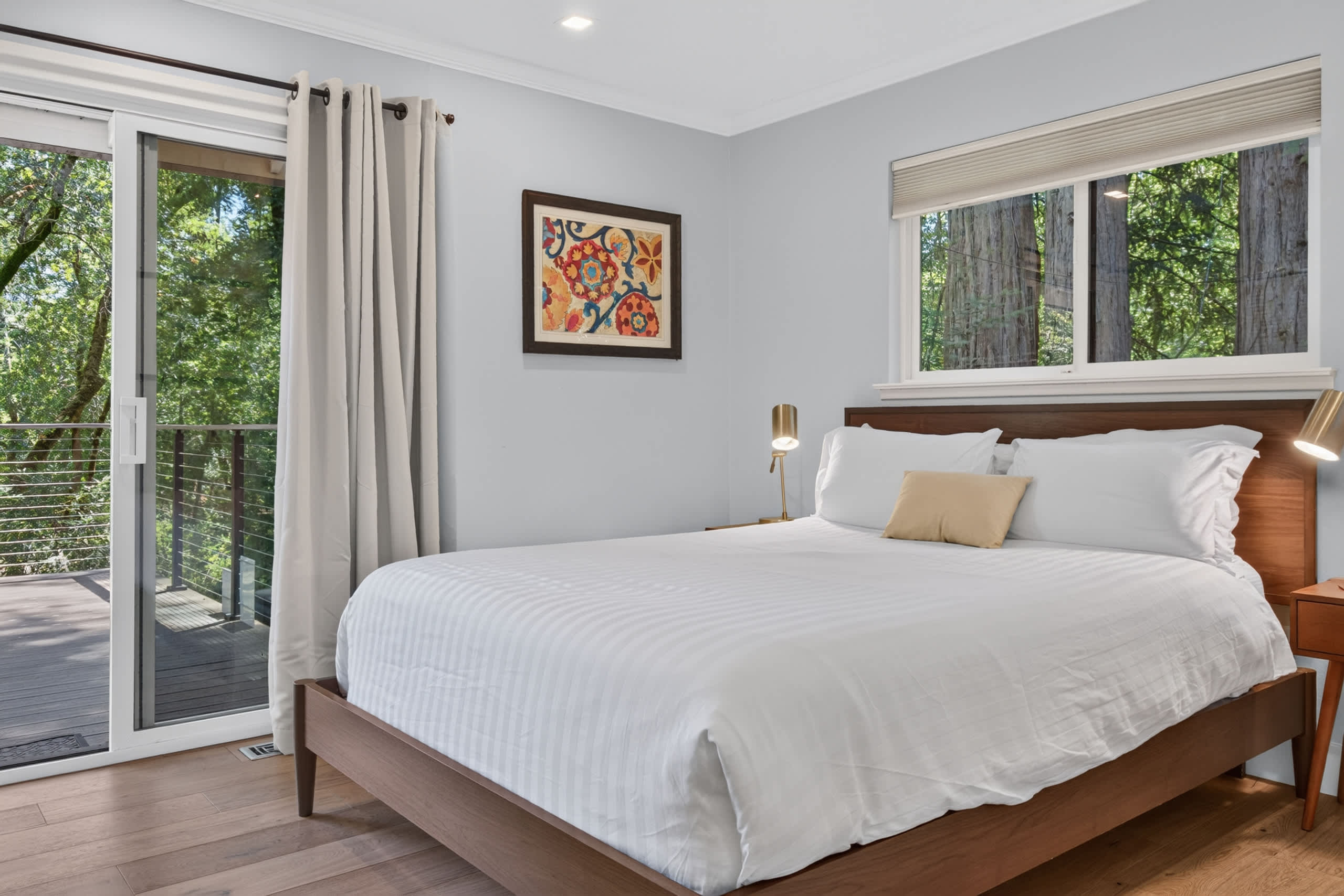 Wake to redwoods framing both windows, then slide open the door for coffee on the deck — king bed, brass sconces, easy mornings.