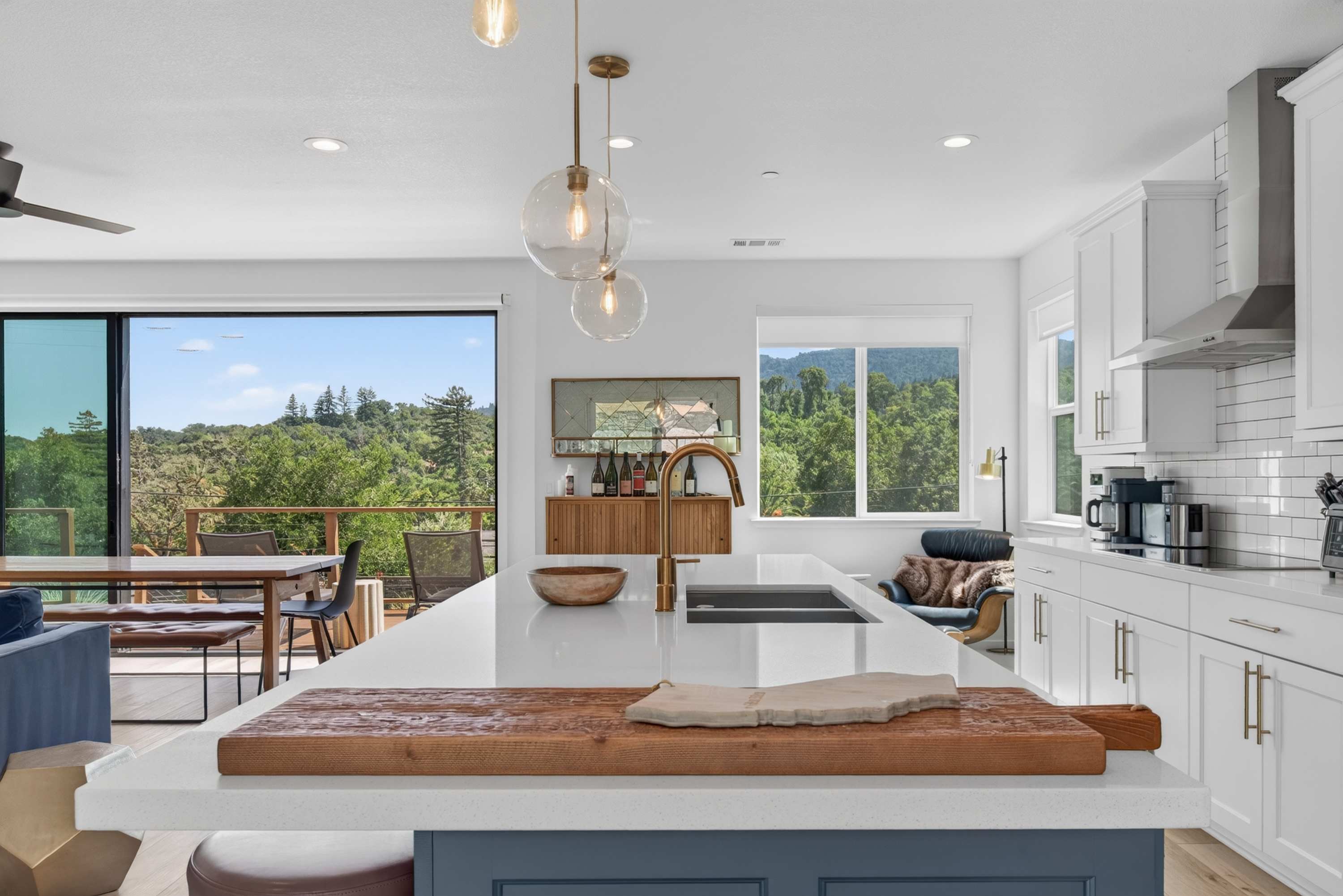 Pour a glass at the quartz island while pendant globes glow overhead and the valley stretches out past the deck.