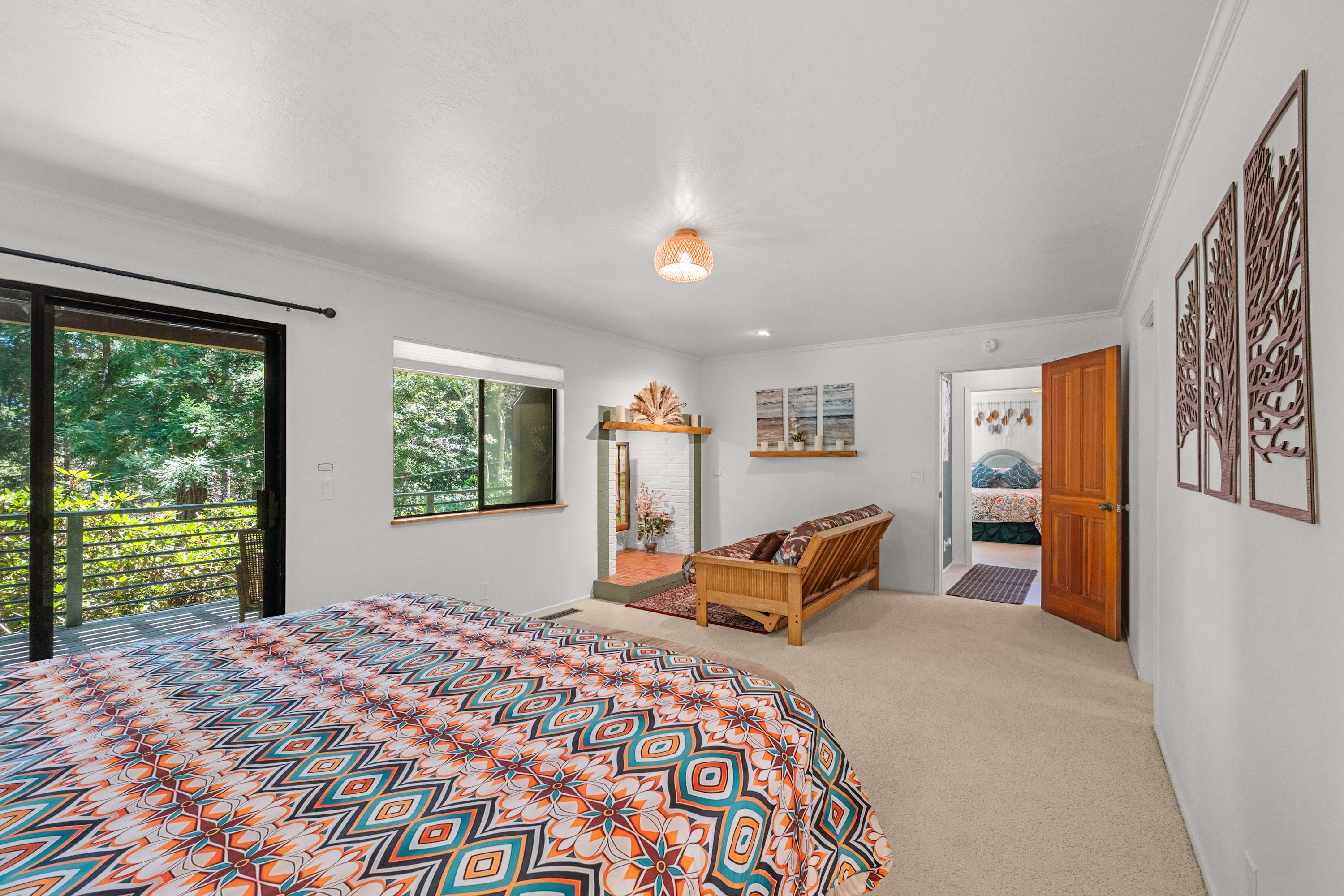 Unwind in the primary suite sitting area—a futon faces the decorative brick fireplace and a slider opens straight to the deck.