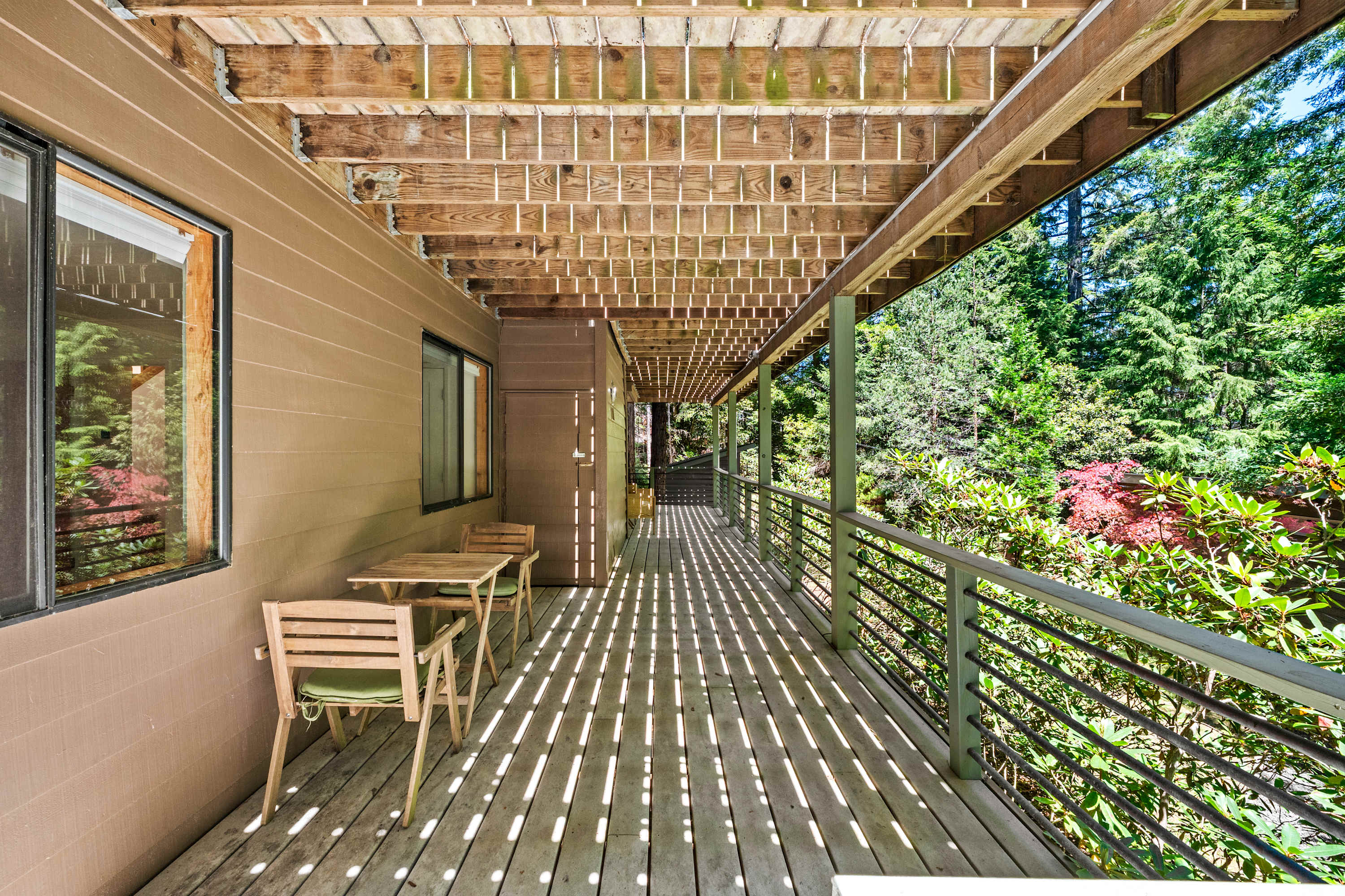 Step onto the covered lower deck where striped sunlight falls across the planks and the woods press in on every side.