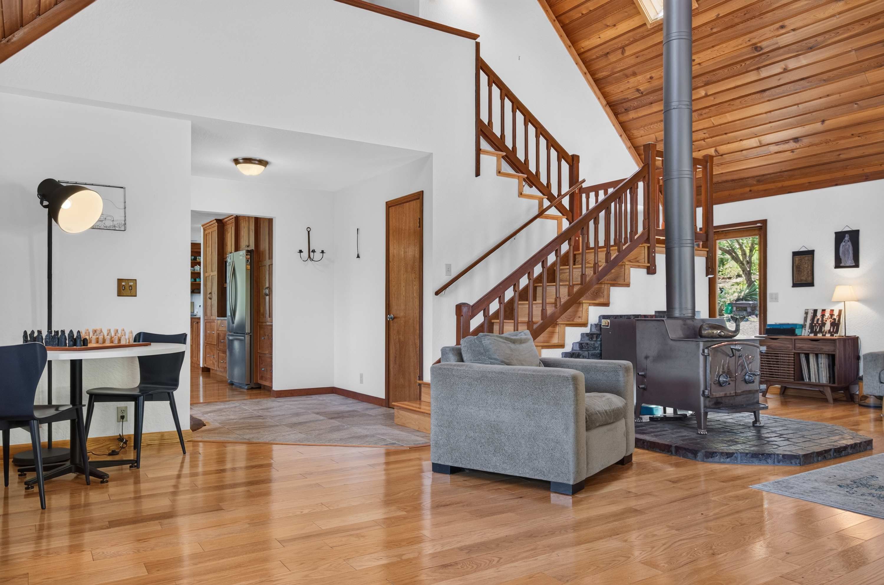 Cedar ceilings soar as the staircase climbs past the vintage wood stove and a chess-set nook by the kitchen — rainy-day headquarters.