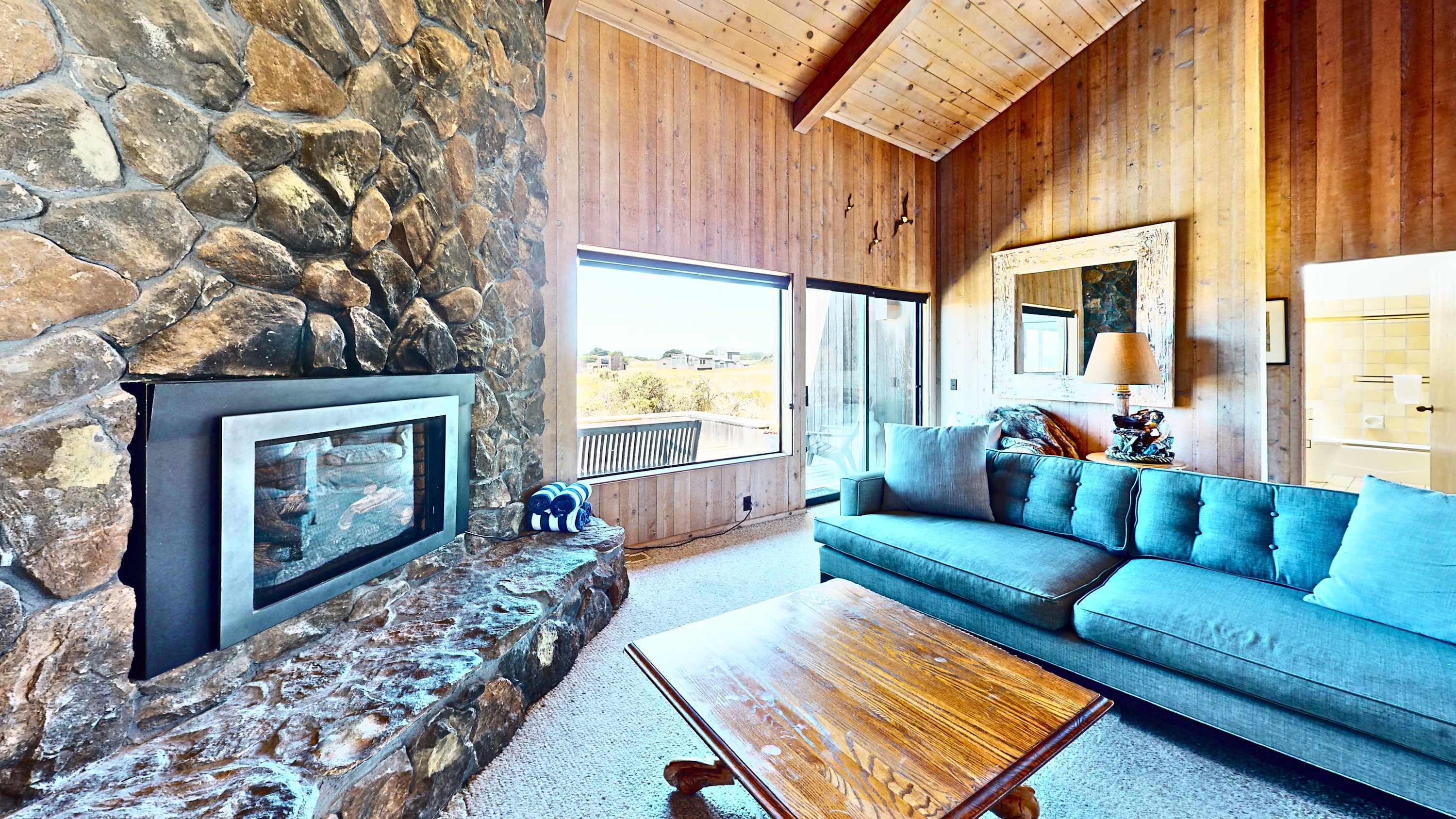 The living room's floor-to-ceiling stone fireplace sets the tone -- settle into the sofa and let the ocean views through the windows do the rest.