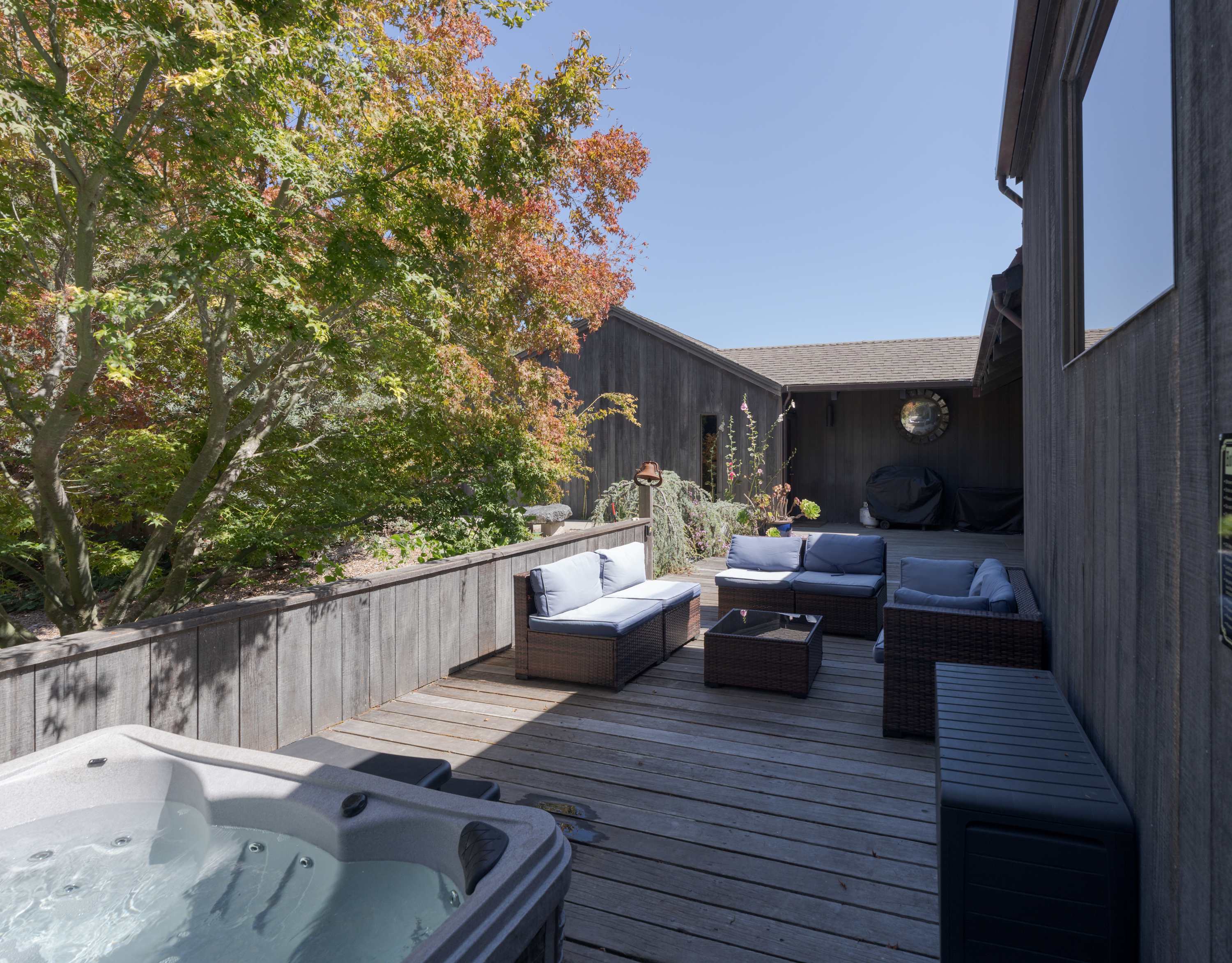 Sink into the private hot tub on the enclosed front courtyard, with sectional seating, a Japanese maple, and stars overhead after dark.