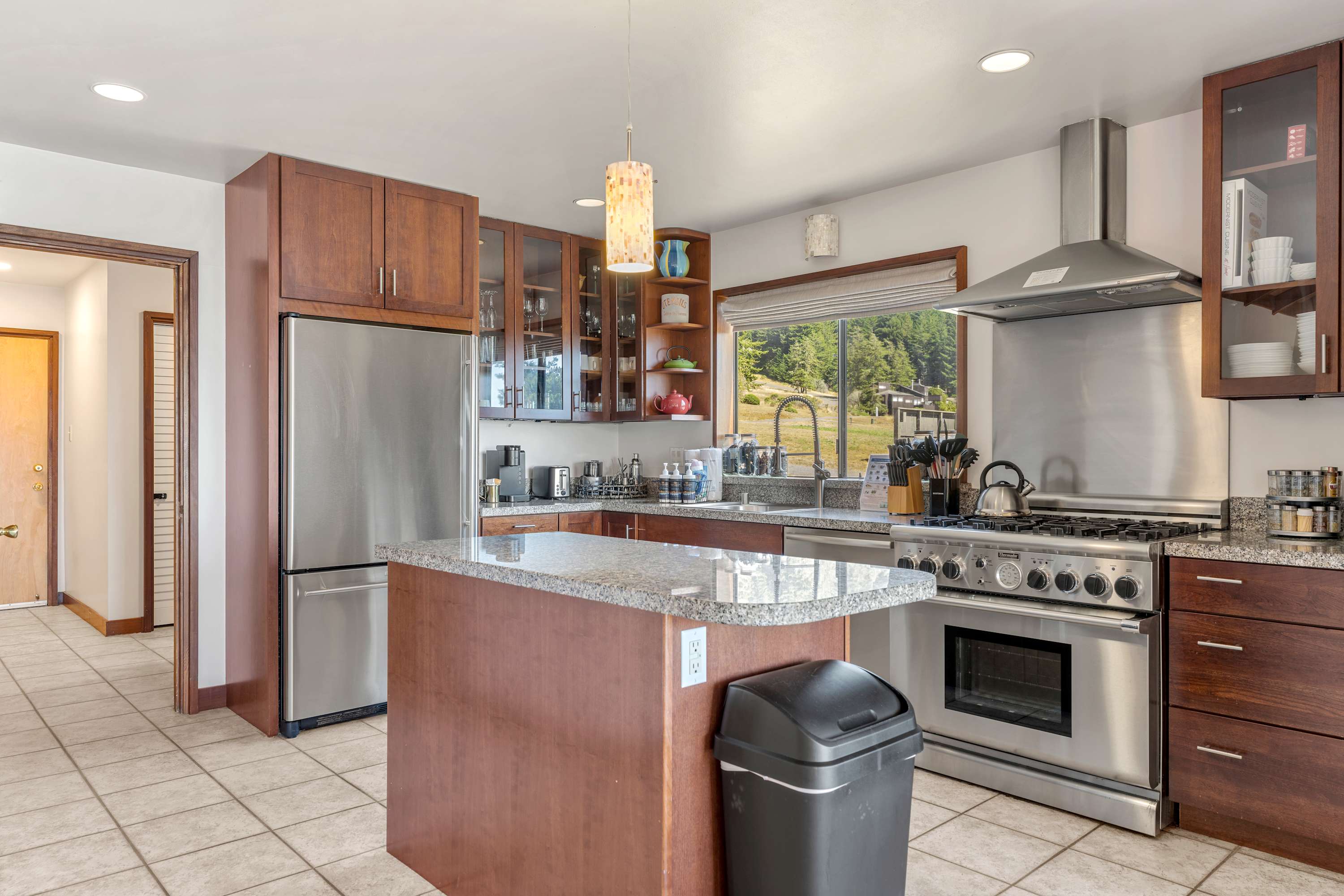 Cook at the gas range while the granite island holds prep space and the stainless fridge waits for groceries.