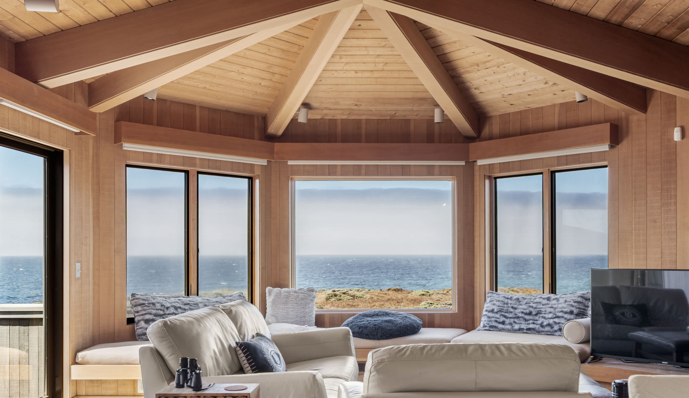 Sink into the pale leather seating under the vaulted redwood ceiling, a wall of windows holding the ocean on three sides.