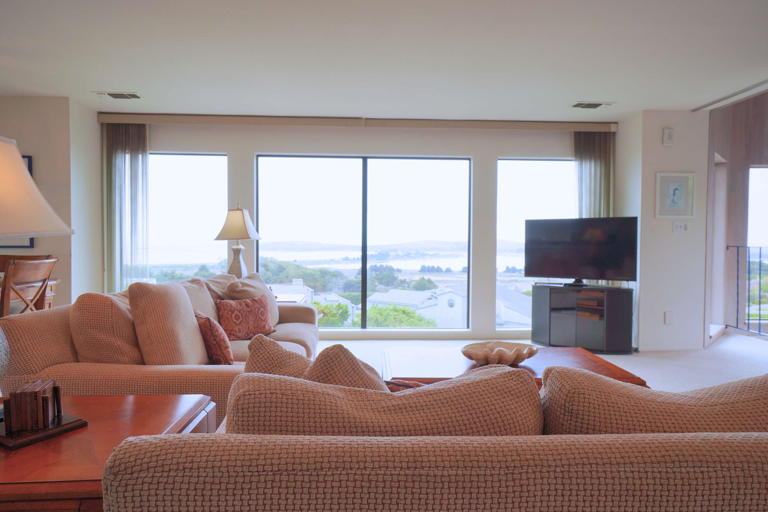 Sink into plush seating in your sunlit living room where panoramic Bodega Bay views stretch beyond floor-to-ceiling windows and a private balcony