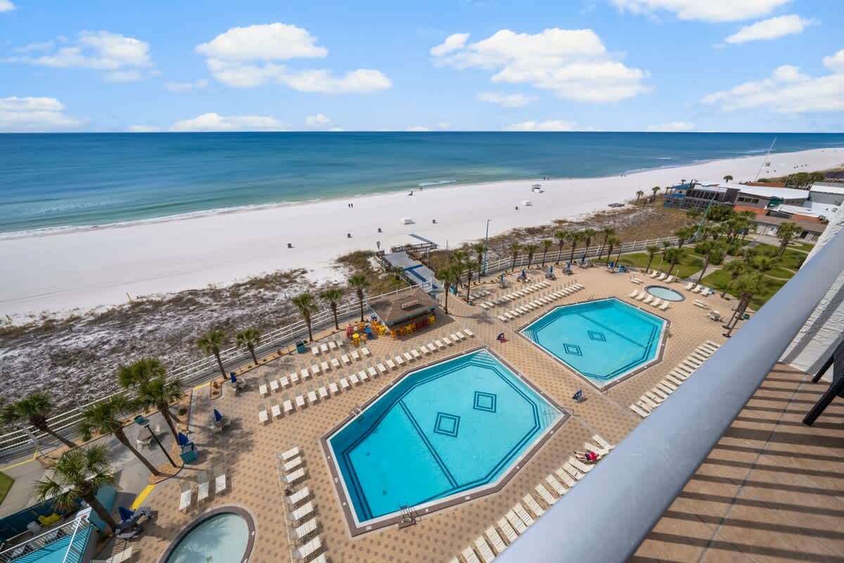 The Summit 921 – View from a balcony showcasing two swimming pools, beach, and ocean in the background.