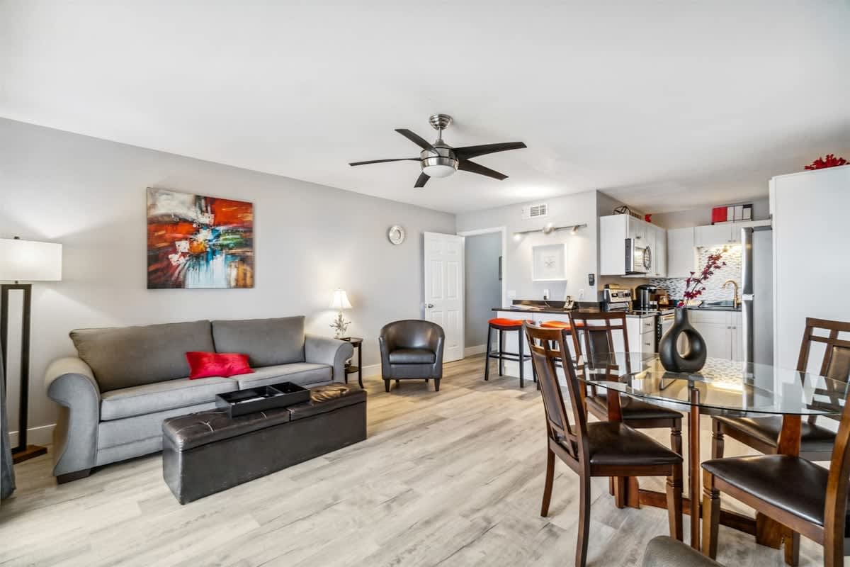 The Summit 531 – Modern living area with a gray couch, dining table, and kitchenette. Bright lighting and neutral decor.
