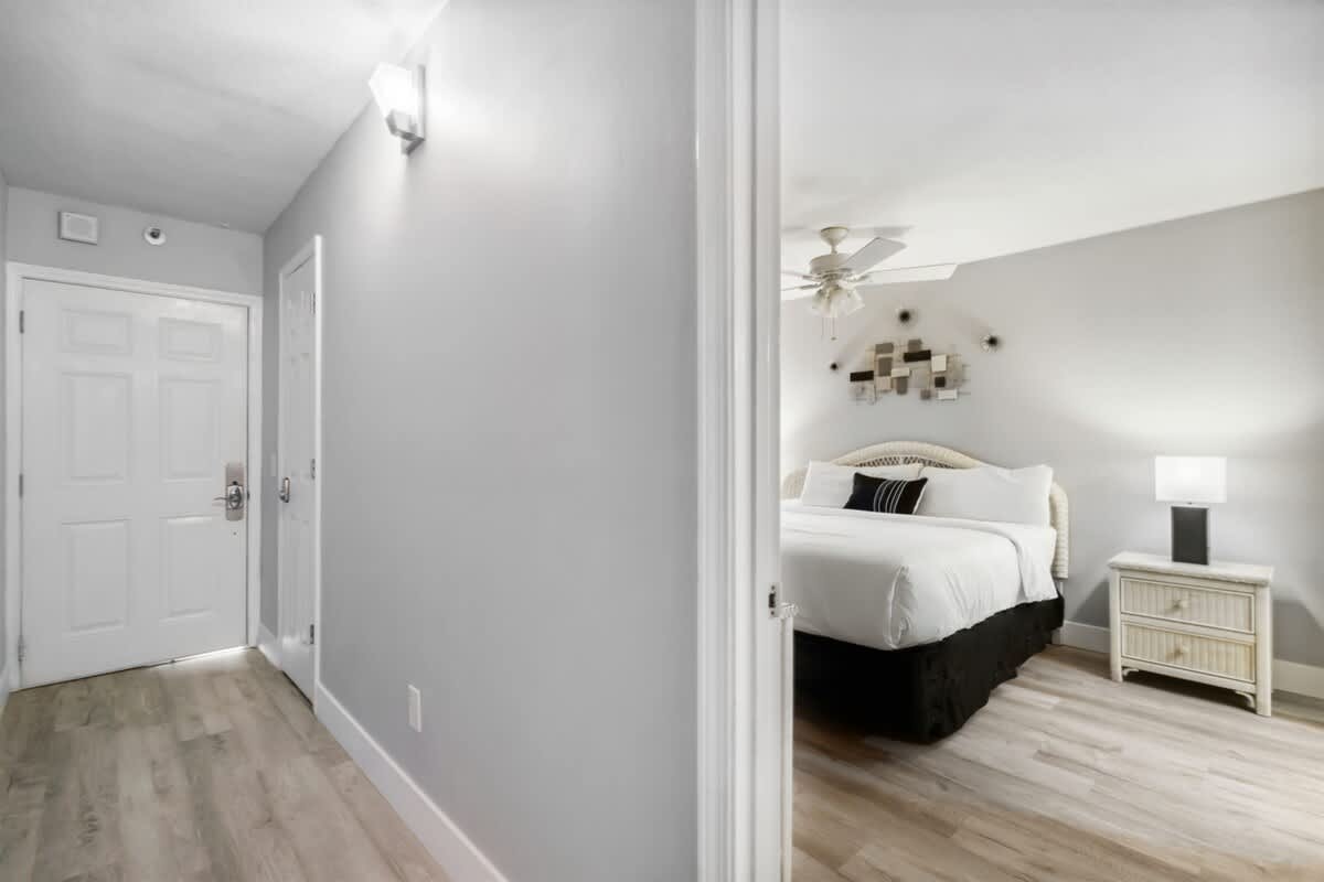 The Summit 531 – Bright bedroom featuring a queen bed, bedside lamp, and wooden flooring, visible from a doorway.
