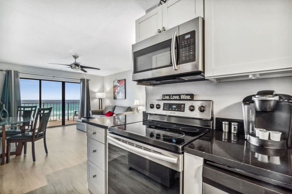 The Summit 531 – Interior view of a rental living space with a kitchen, dining table, and ocean view through large sliding glass doors.