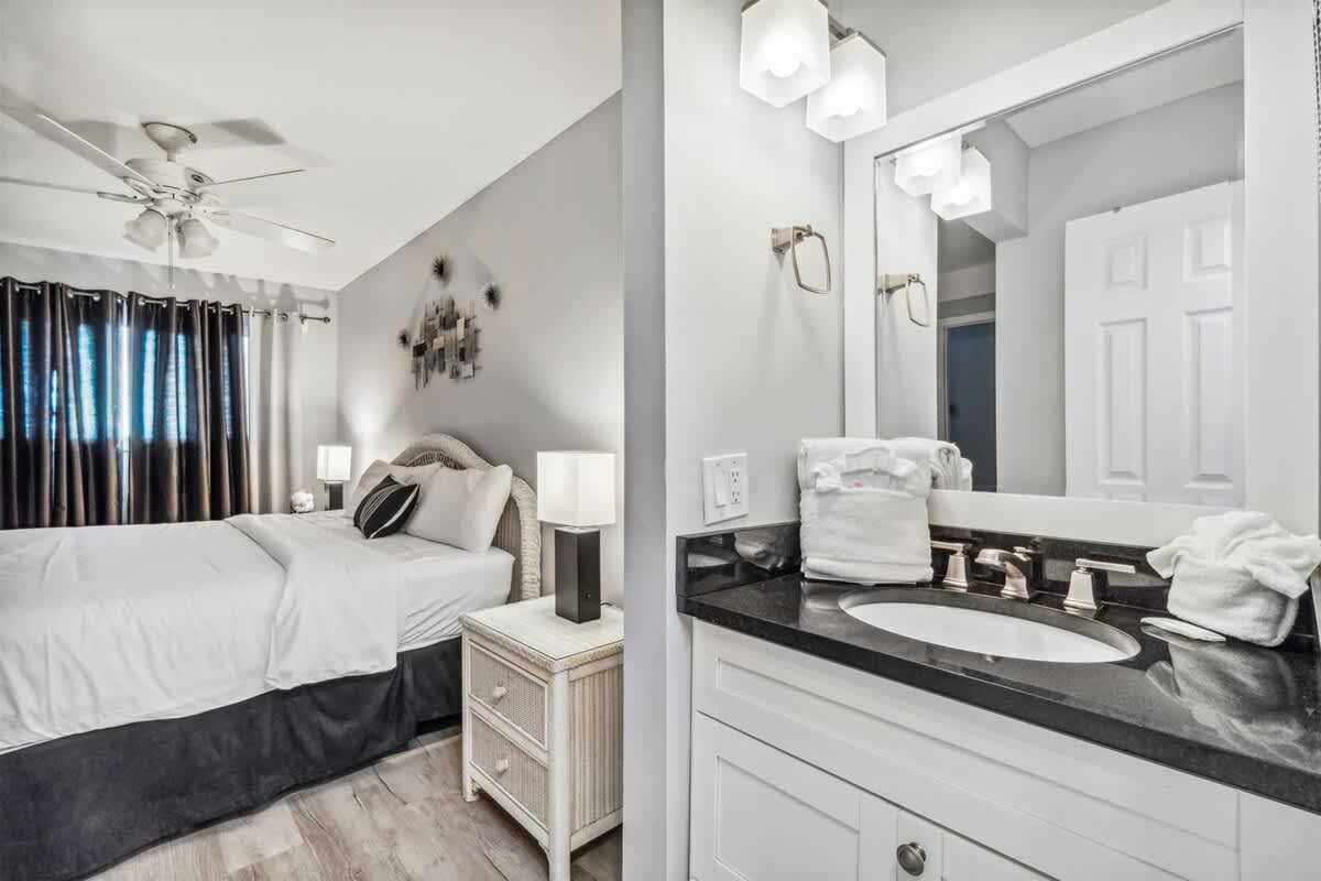 The Summit 531 – Bedroom with a queen bed, side table, and adjoining bathroom with a sink and mirror.