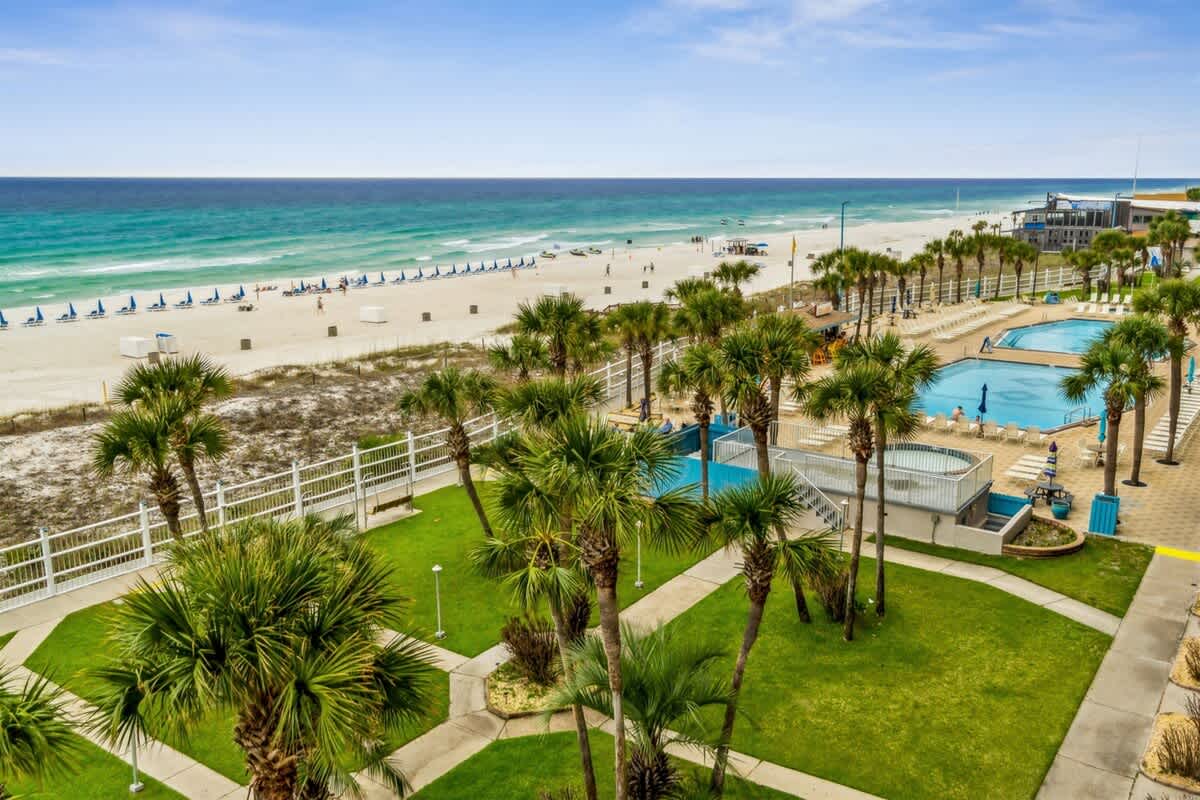 The Summit 531 – View of beach, palm trees, and outdoor swimming pools from a balcony.