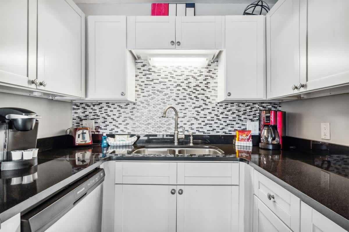The Summit 531 – Modern kitchen with white cabinets, black countertops, stainless steel sink, and appliances including coffee maker and toaster.
