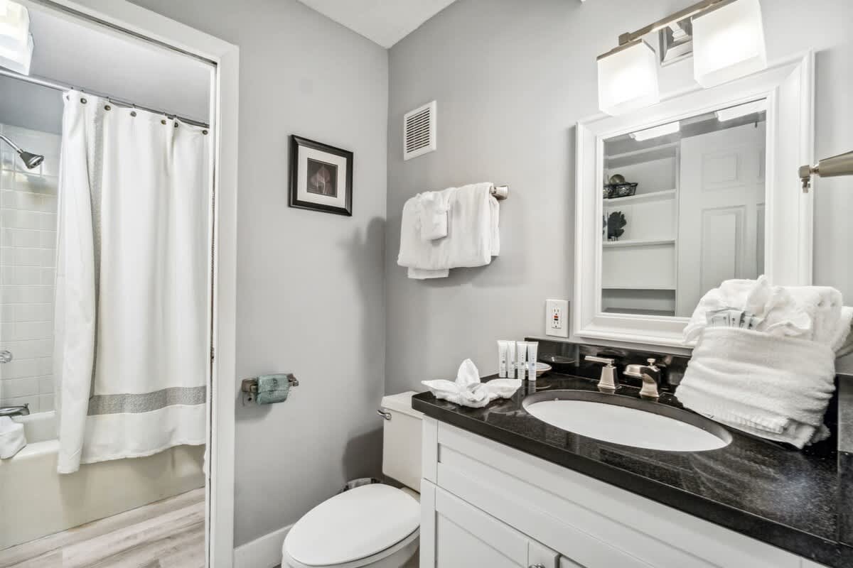 The Summit 531 – Modern bathroom with white towels, dark countertop, mirror, and shower curtain.