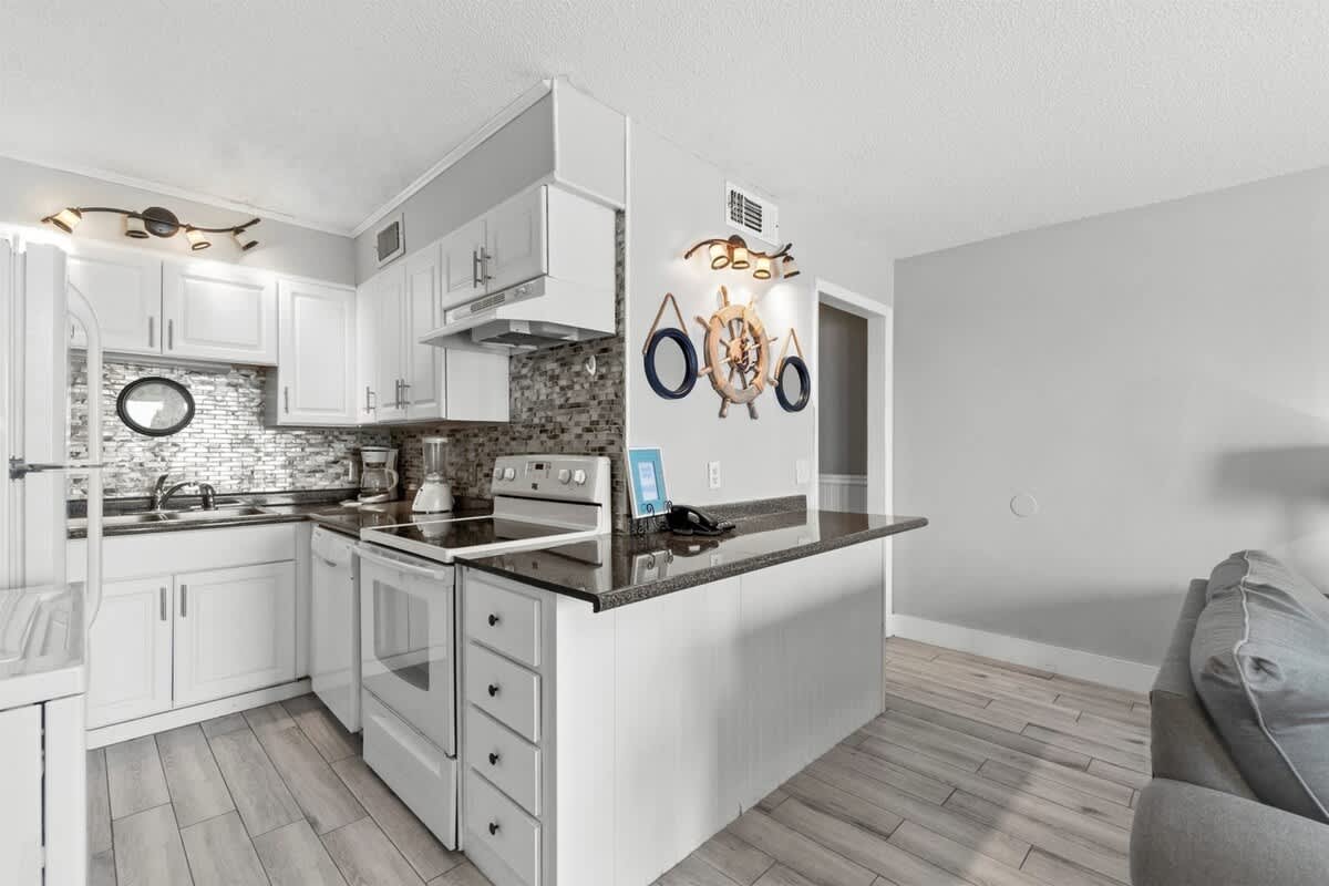 The Summit 728 – Modern kitchen with white cabinets, gray countertop, and nautical decor in a vacation rental setting.