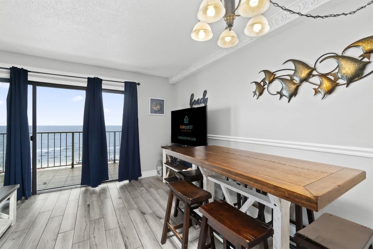 The Summit 728 – Dining area with wooden table, ocean view, and large sliding glass doors.