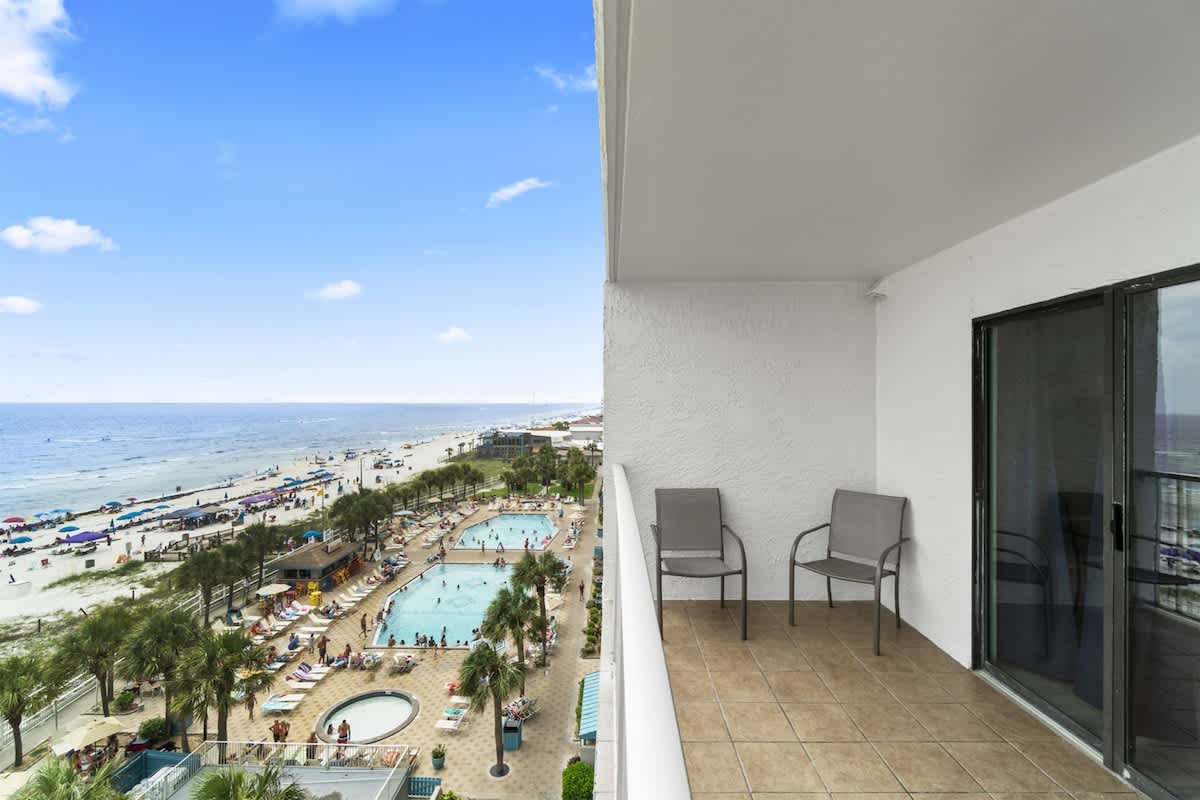 The Summit 728 – Balcony with two chairs overlooking pools and beach area.