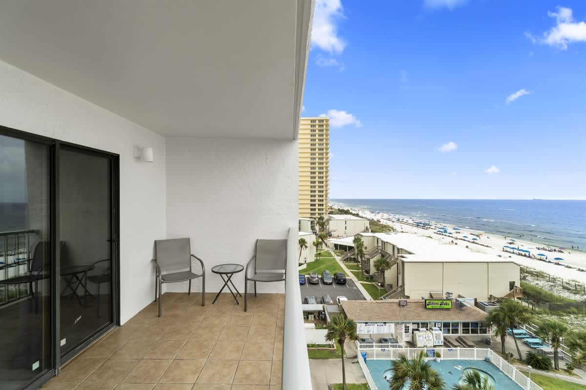 The Summit 728 – Balcony view of beach, ocean, and nearby buildings with two chairs and a table.