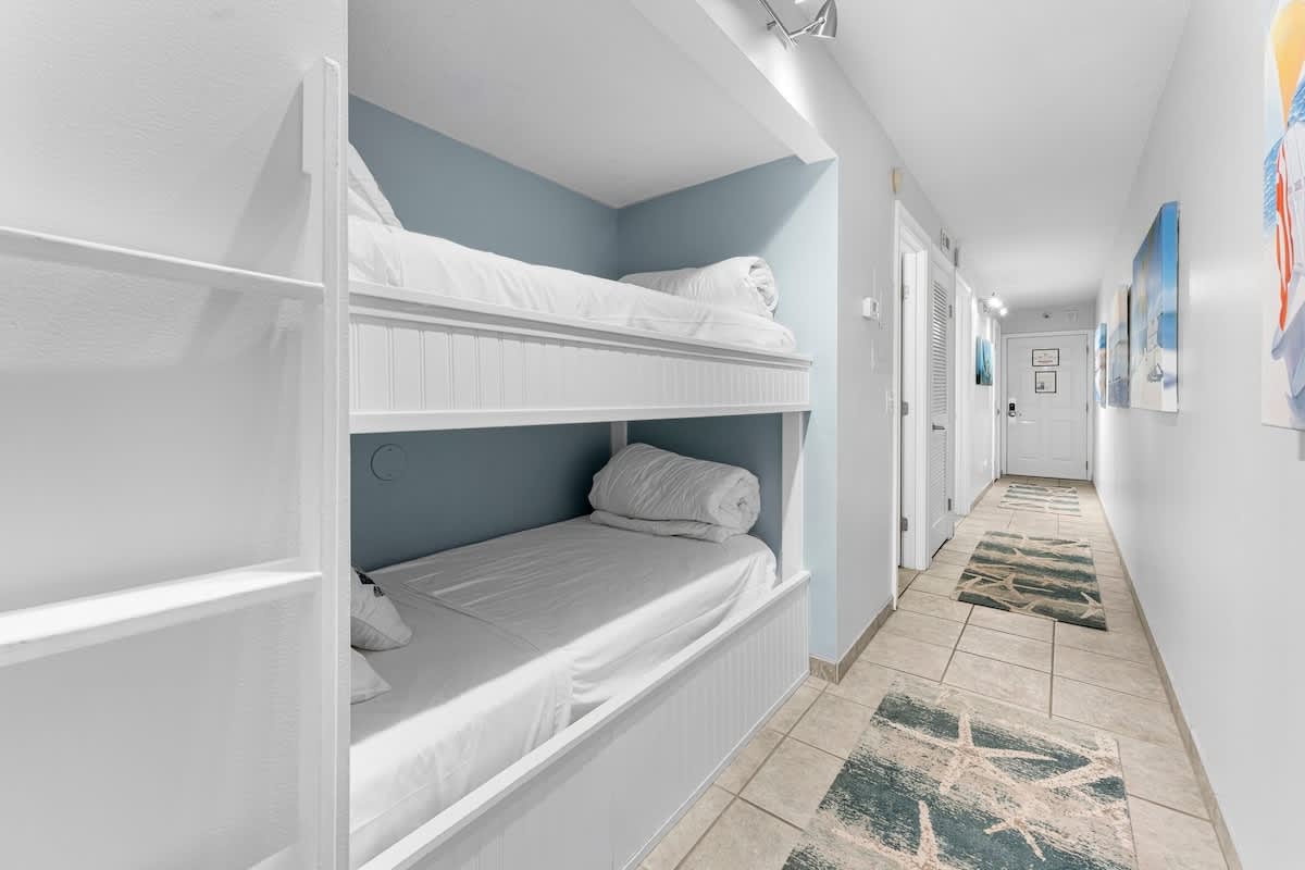 The Summit 1130 – Bunk beds in a hallway with tiled flooring and beach-themed decor.