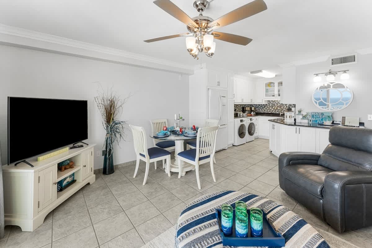 The Summit 1130 – Living room with dining area, TV, kitchen appliances, and decorative elements.