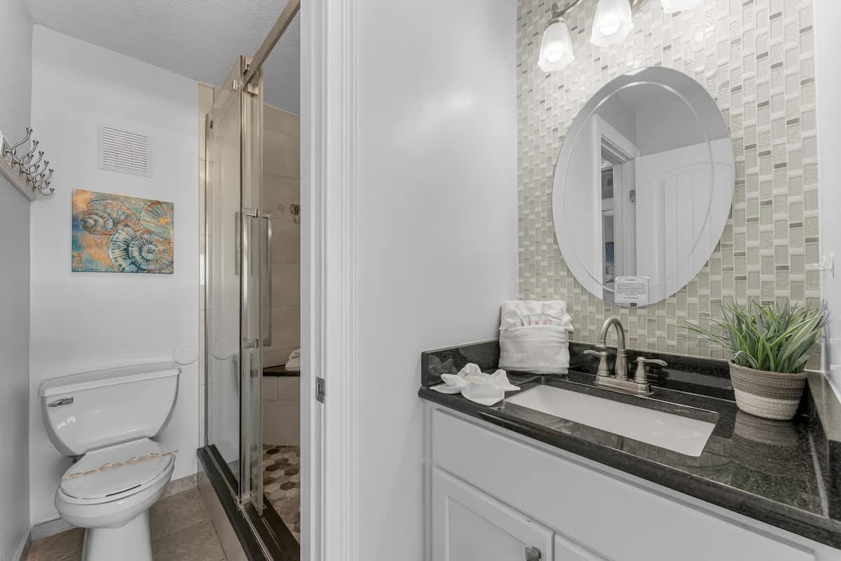 The Summit 1130 – Bathroom with a modern sink, shower, toilet, and decorative wall tiles.