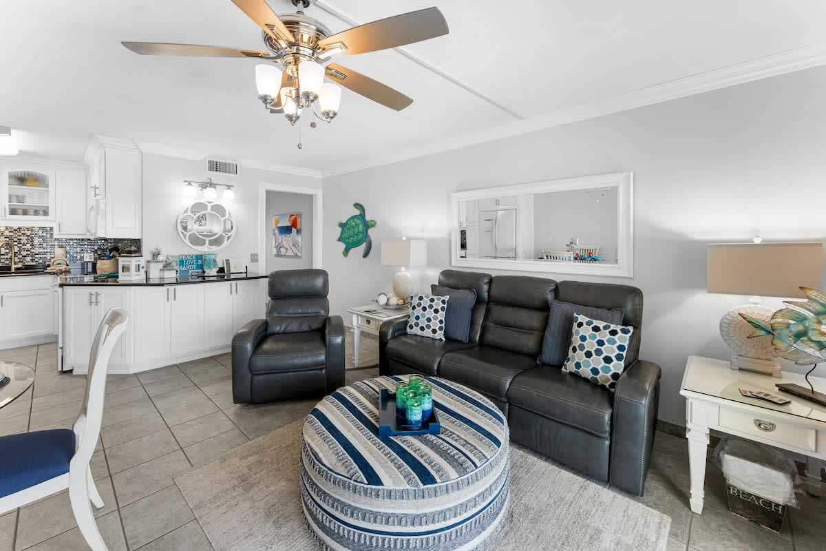 The Summit 1130 – Living room with leather seating, circular coffee table, and kitchen area in the background.