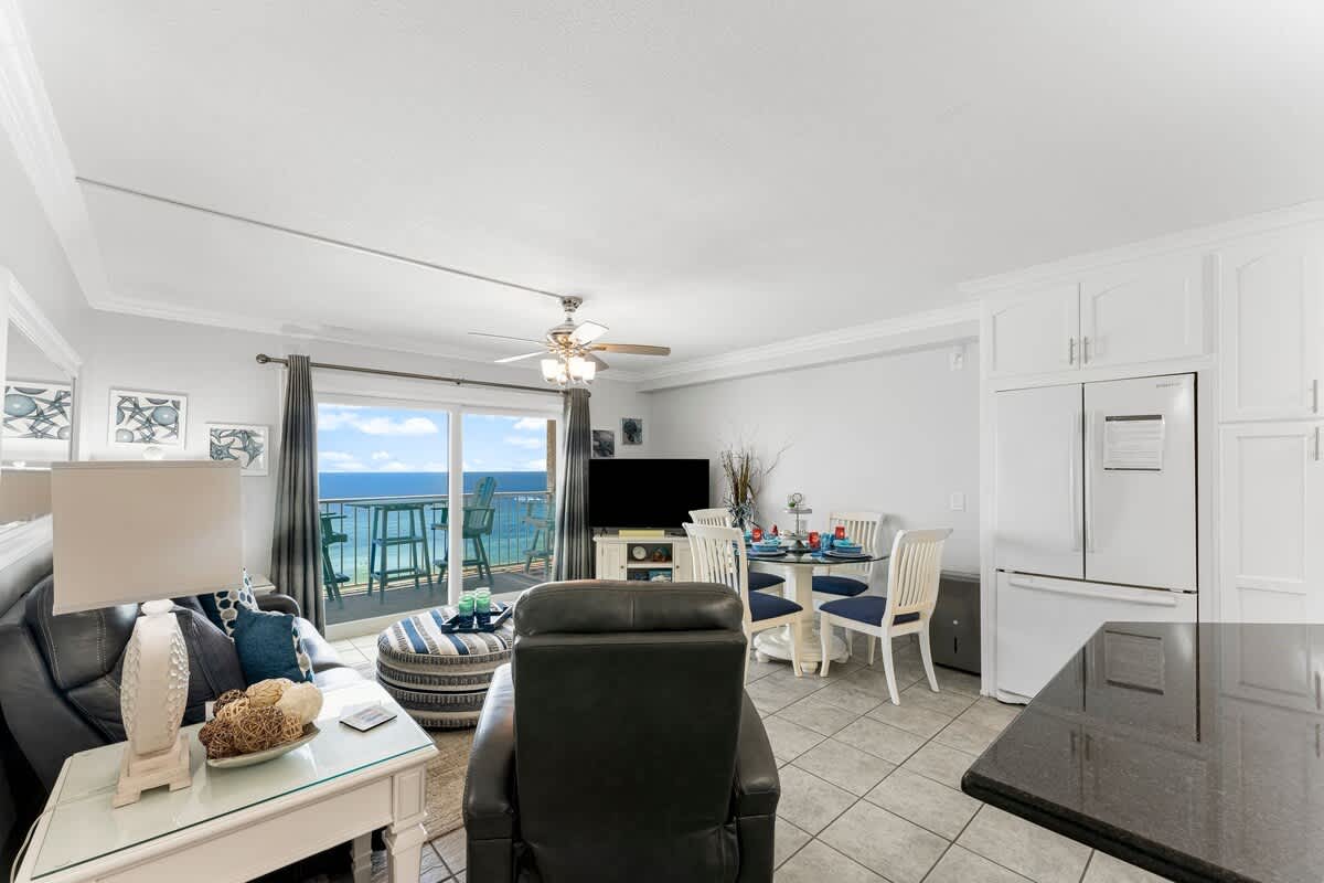 The Summit 1130 – Living room and dining area with ocean view, sofa, decorative table, and kitchen appliances.
