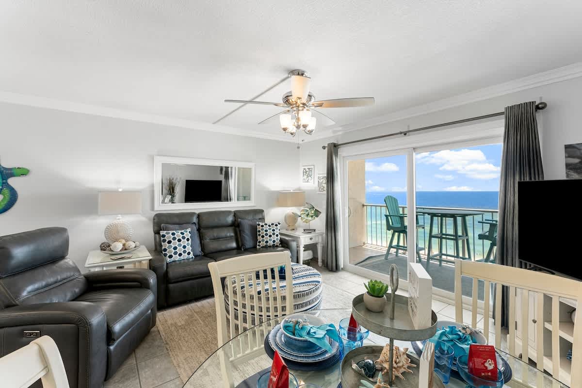 The Summit 1130 – Living room with ocean view, leather seating, dining area, and sliding glass door to balcony.