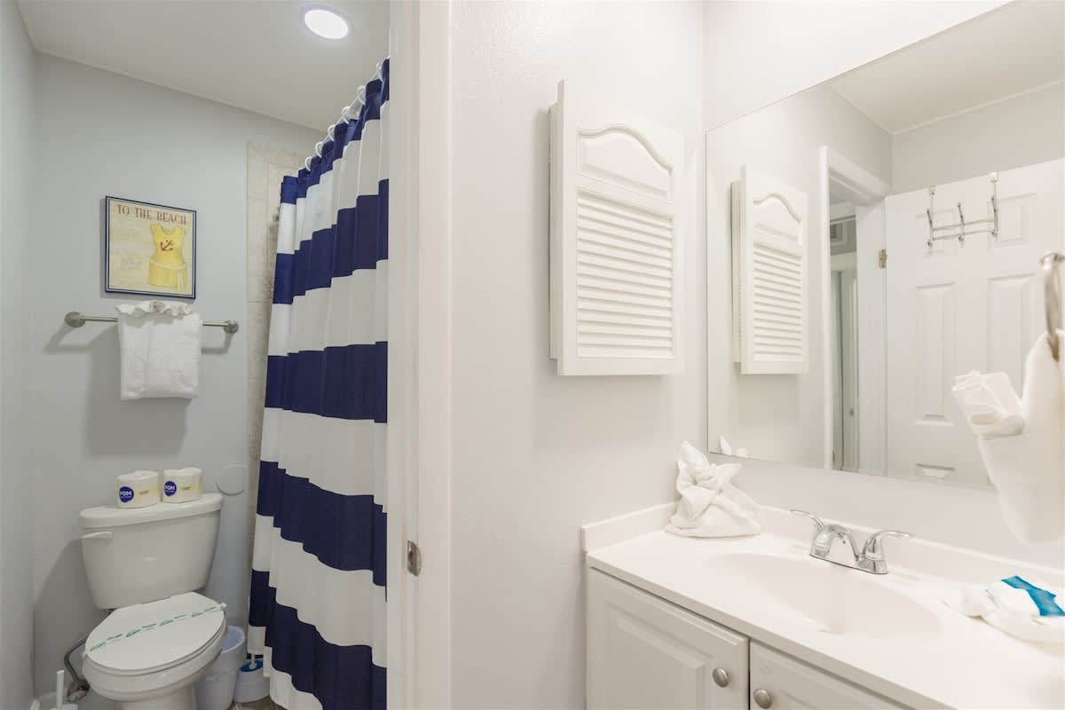 The Summit 504 – Bathroom with a white sink, blue and white striped shower curtain, and a mirror above the sink.