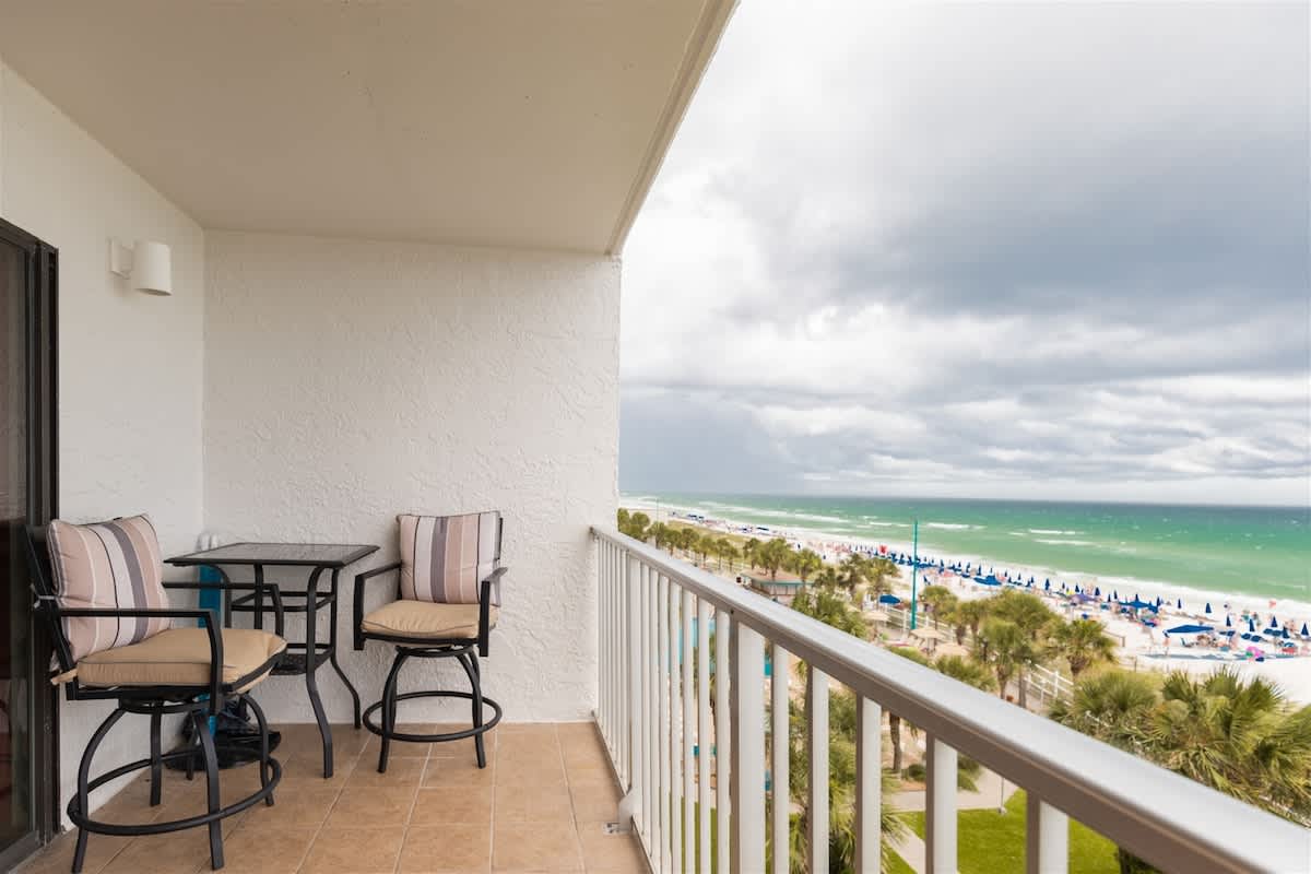 The Summit 504 – Balcony with two chairs and a table, overlooking a beach and ocean view.