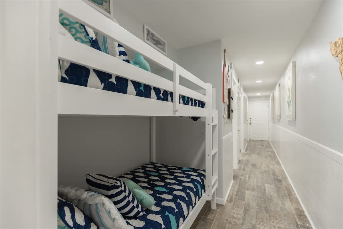 The Summit 504 – Bunk beds with blue and white bedding in a corridor with light wood flooring and wall art.