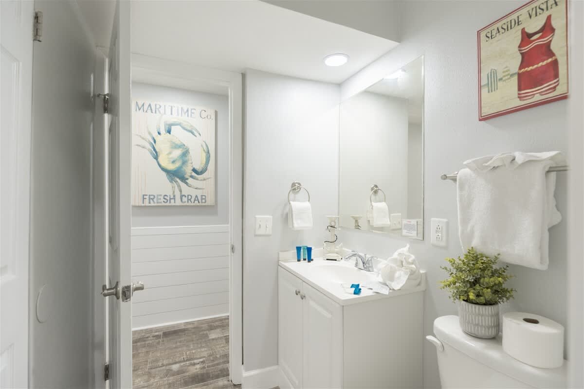 The Summit 504 – Bright bathroom with a sink, mirror, and decorative wall art.