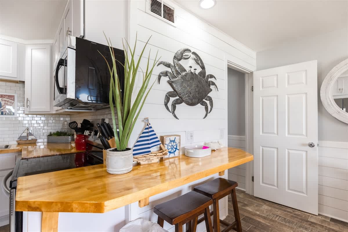 The Summit 504 – Modern kitchen area with wooden bar, stools, decorative crab wall art, and plants.