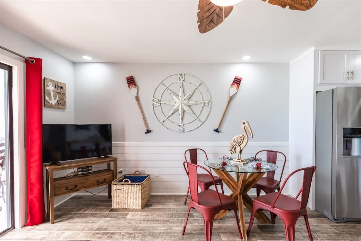 The Summit 504 – Cozy dining area with a round table, red chairs, and nautical decorations.