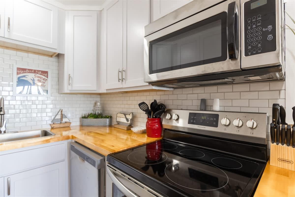 The Summit 504 – Kitchen with stainless steel appliances, wooden countertops, and white cabinetry, featuring a decorative nautical theme.