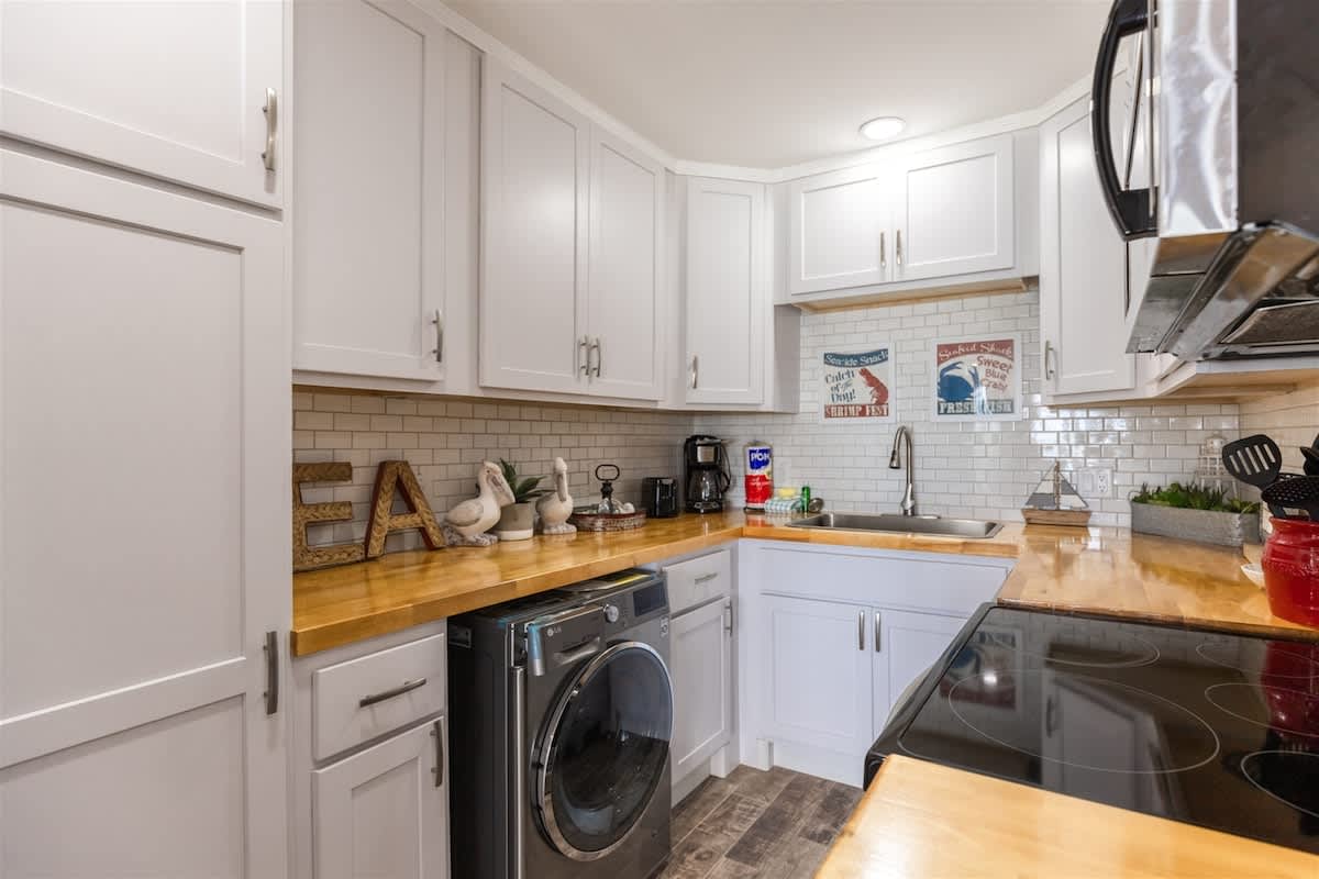 The Summit 504 – Bright kitchen with white cabinets, wooden countertops, modern appliances, and decorative coastal-themed decor.