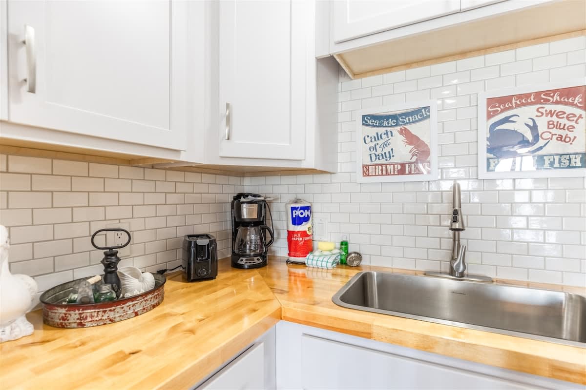 The Summit 504 – Kitchen area featuring white cabinets, stainless steel sink, coffee maker, and decorative seafood-themed wall art.