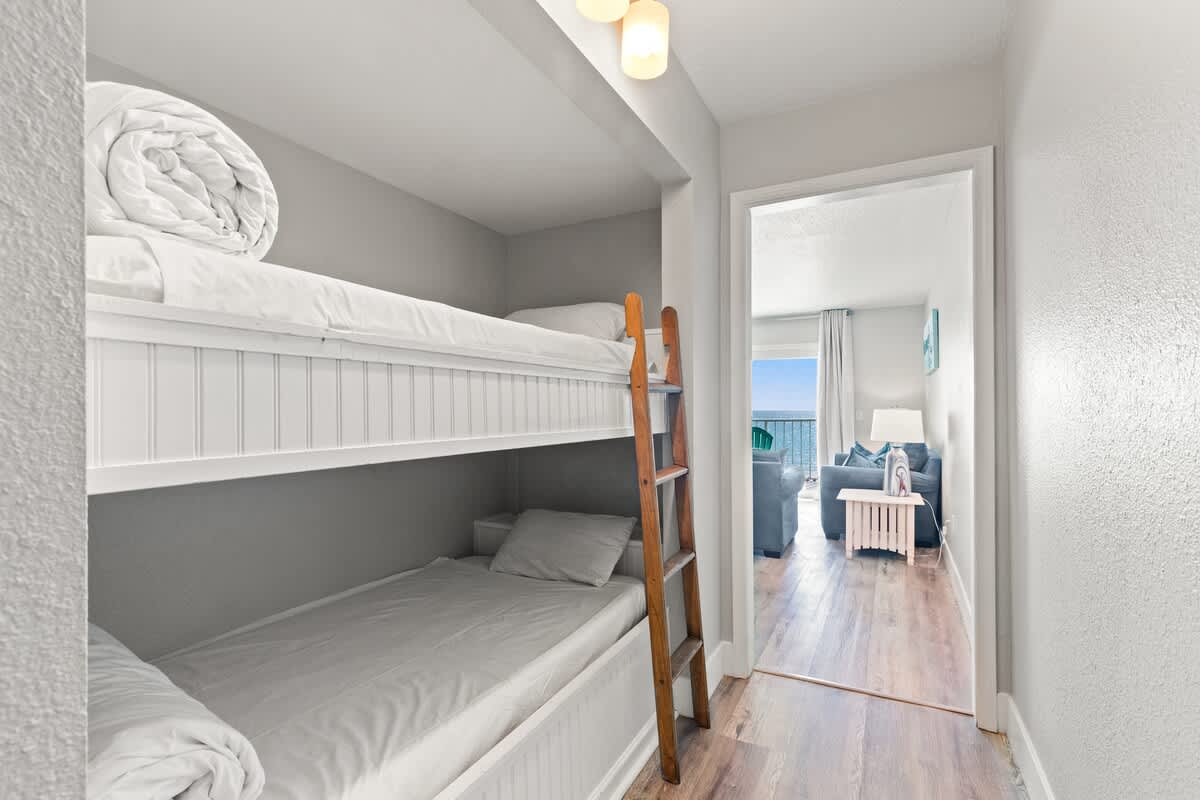 The Summit 515 – Bunk beds in a small room with a view of a living area and balcony beyond.
