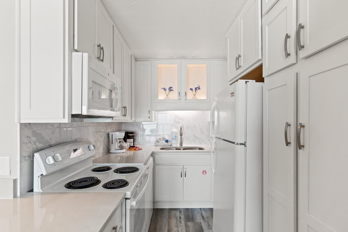 The Summit 515 – Modern kitchen with white cabinets, appliances, and a marble backsplash.