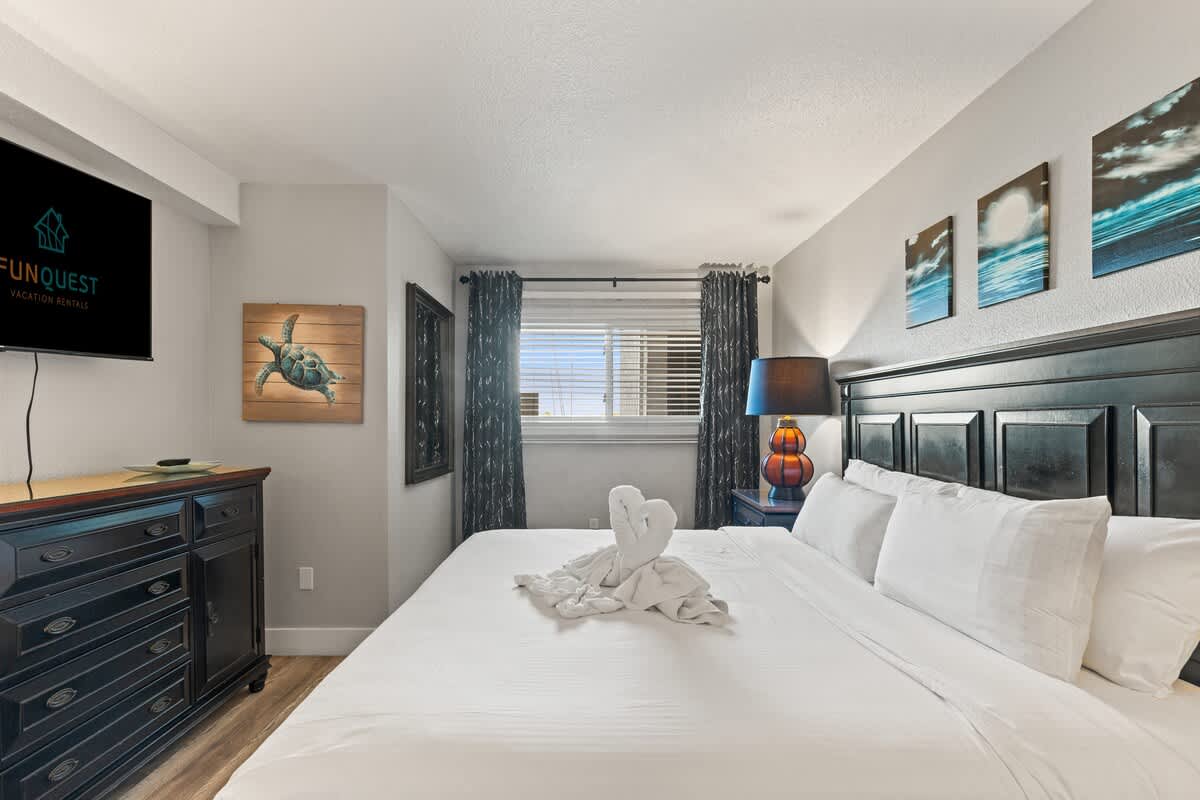 The Summit 515 – Cozy bedroom with a king-size bed, decorative turtle art, and window with blinds.