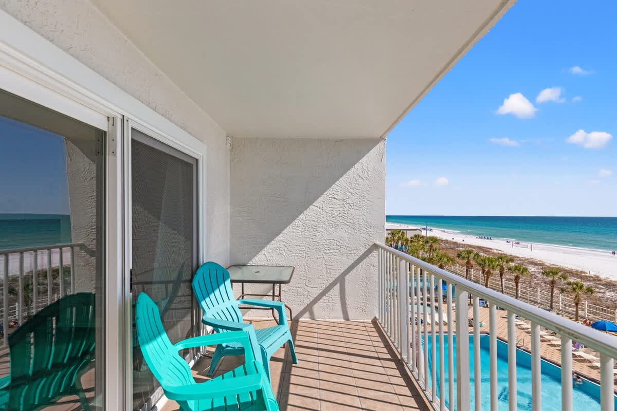 The Summit 515 – Balcony view with turquoise chairs overlooking beach and pool area.