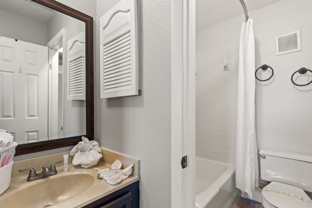 The Summit 515 – Bathroom with a sink, mirror, shower, and toilet; towels placed on the countertop.