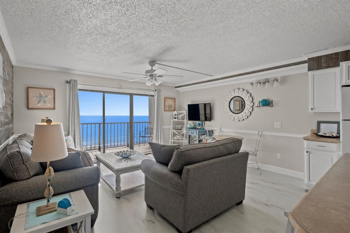The Summit 816 – Living room with ocean view, light-colored furniture, flat-screen TV, and balcony access.