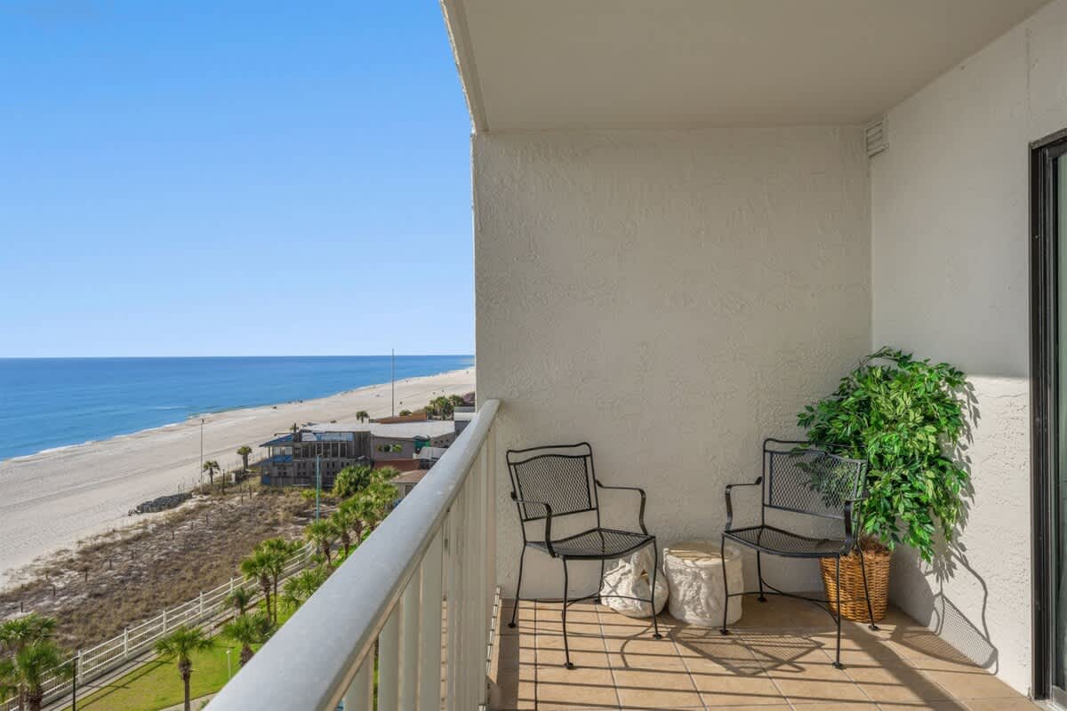 The Summit 816 – Balcony with two chairs, small table, and ocean view overlooking sandy beach.