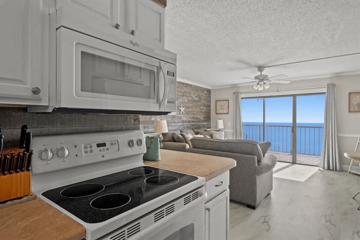 The Summit 816 – Cozy living area with kitchen view, sliding glass door, and ocean view balcony.